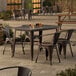 A Lancaster Table & Seating Alloy Series copper table with 4 chairs on an outdoor patio.
