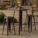 A Lancaster Table & Seating outdoor bar height table with 2 backless barstools on a patio.