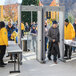 A group of people standing in line in a metal gate with a Garrett metal detector.