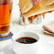 A person pouring Campbell's Au Jus Gravy over a sandwich.