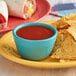 A plate of tortilla chips with red Pace Picante sauce on a table in a Mexican restaurant.