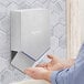 A person using a Dyson Nickel Airblade V hand dryer to dry their hands.