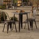 A Lancaster Table & Seating outdoor table and chairs with a copper metal frame on a patio.