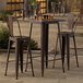 A Lancaster Table & Seating copper bar height table with 2 chairs on an outdoor patio.