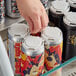 A hand opening a PakTech white plastic 4-pack can carrier with a can of soda inside.