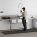 A man wearing gloves washing dishes in a Regency 3 compartment sink.