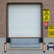 An Ideal Warehouse loading dock light mounted on a white garage door with a brown frame.