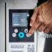 A close-up of a person operating the control panel of a Hobart AM16-SCB low temperature chemical sanitizing door-style dishwasher.