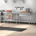 A Regency stainless steel open base work table in a kitchen with shelves.