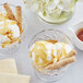 A close-up of a white bowl of ice cream with waffle rolls and syrup.