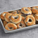 A metal pan of Original New York Style Blueberry Bagels with blueberry filling.