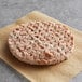 A raw Beyond Meat plant-based vegan burger patty on a brown paper.