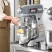 A woman in an apron using a Hobart Legacy+ stand mixer to mix food.