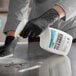 A person in black gloves spraying CLR Multi-Purpose Cleaner on a counter in a professional kitchen.