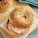 An Original New York Style Everything Bagel with cream cheese spread on a cutting board.