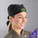 A smiling woman wearing a black Uncommon Chef skull cap with ties in a professional kitchen.