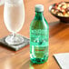 A Mountain Valley Spring Water plastic bottle next to a glass of water on a table.