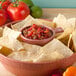 A bowl of tortilla chips with salsa and tomatoes in a HS Inc. paprika salsa bowl.