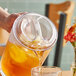 A person pouring a drink from a GET Lid into a glass on a table.