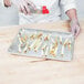 A chef using a Vollrath Redco French Fry Cutter to make fries on a counter.