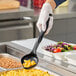 A person in gloves using a black Vollrath Spoodle to serve macaroni and cheese.