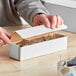A person using a hand to open a white Lavex corrugated mailer.