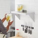 A person holding a yellow and white label can of corn on a Regency stainless steel wall shelf.