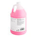A jug of pink liquid with a white label.
