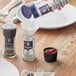 A person refilling a salt shaker with Morton Extra Coarse Sea Salt using a red handled grinder.