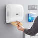 A person putting a white paper towel into a Lavex translucent white mini multifold plastic paper towel dispenser.