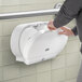 A man installing a Lavex White Double Roll Jumbo Toilet Tissue Dispenser on a wall.