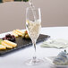 A Stolzle Nadine flute glass filled with champagne on a table in a cocktail bar.