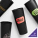 Four black customizable IML hard plastic cold cups with different designs on them.