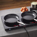 A non-stick fry pan with a stainless steel handle placed on an induction cooktop.