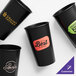 A group of black customizable hard plastic cups with different colored labels.