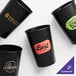 A group of black customizable hard plastic cups with different logos.