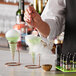 A person using a Flavour Blaster to add grapefruit aroma to a green cocktail with smoke coming out of it.