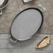 An oval stainless steel saute pan with two handles.
