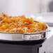 A stainless steel oval saute pan with handles, filled with baked pasta, labeled 'Spring USA Primo! 1.5 Qt. 5-Ply Oval Saute Pan with Stainless Steel Handles.'