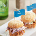 A group of burgers with medium wavy flag picks on top.