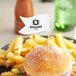 A burger on a plate with a wavy flag pick in it.