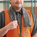 A man wearing a safety vest holding a gray Cordova Coldsnap cooling towel.