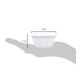 A hand holding a white fluted melamine ramekin with measurements.