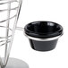 A stainless steel cone basket with two black ramekins on a table.