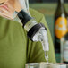 A person using a Choice 3-Ball Measured Liquor Pourer to pour liquid into a glass.