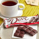 A DOVE dark chocolate bar with a logo on the wrapper on a table near a cup of tea.