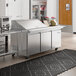 An Avantco stainless steel sandwich prep table on a large stainless steel counter.
