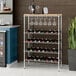 A Regency wire wine rack with wine glasses on a hardwood top and a plant.