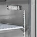 An Avantco stainless steel cutting top refrigerator with a thermometer on a shelf.