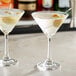 Two Acopa martini glasses filled with martinis, one garnished with olives.